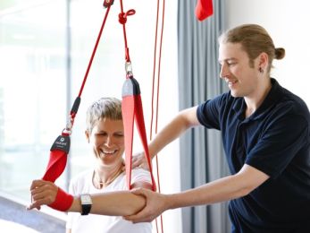 Frau und Therapeut bei Physiotherapie des Arms